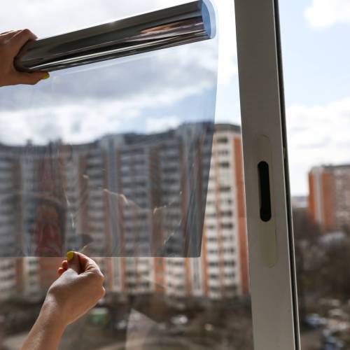 tinted glass in the house. window dimming by dark film. tinting home window. tint film on the background of multi-storey buildings. window view through tinted glass